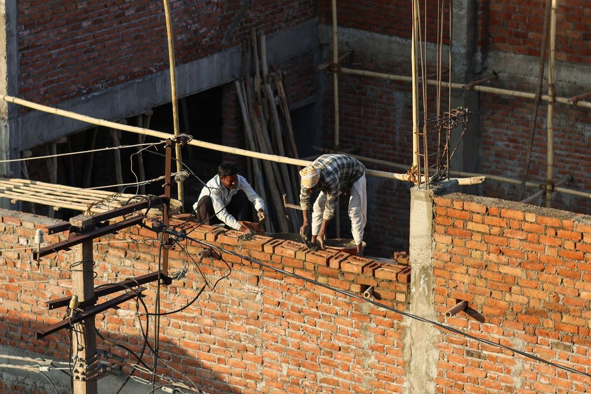 Pedreiros levantando uma parede de tijolos em uma obra